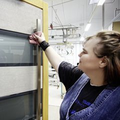 Mitarbeiterin reinigt moderne Haustür Oberfläche im Showroom